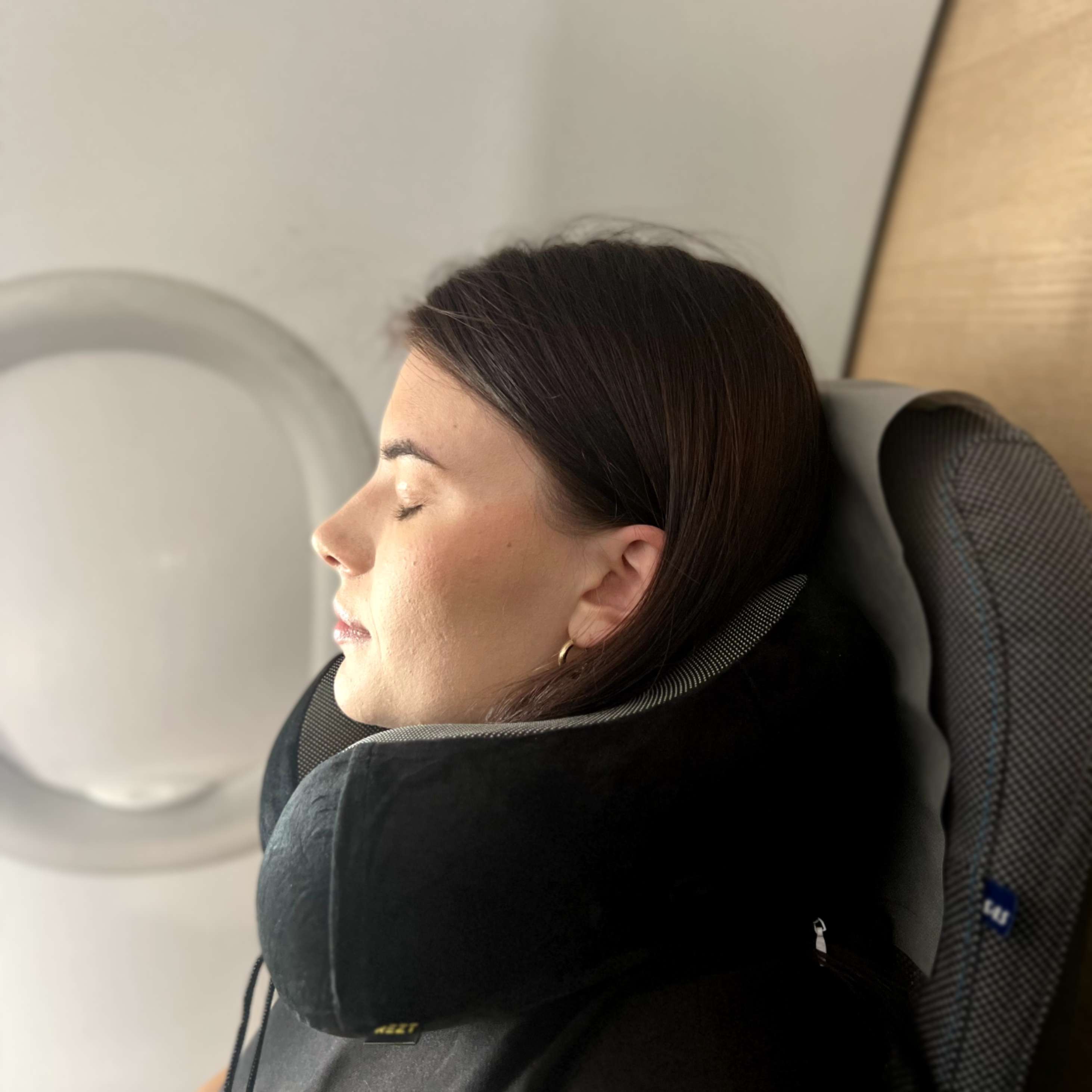 En kvinna slappnar av i ett flygplanssäte med en stödjande REZT resekudde