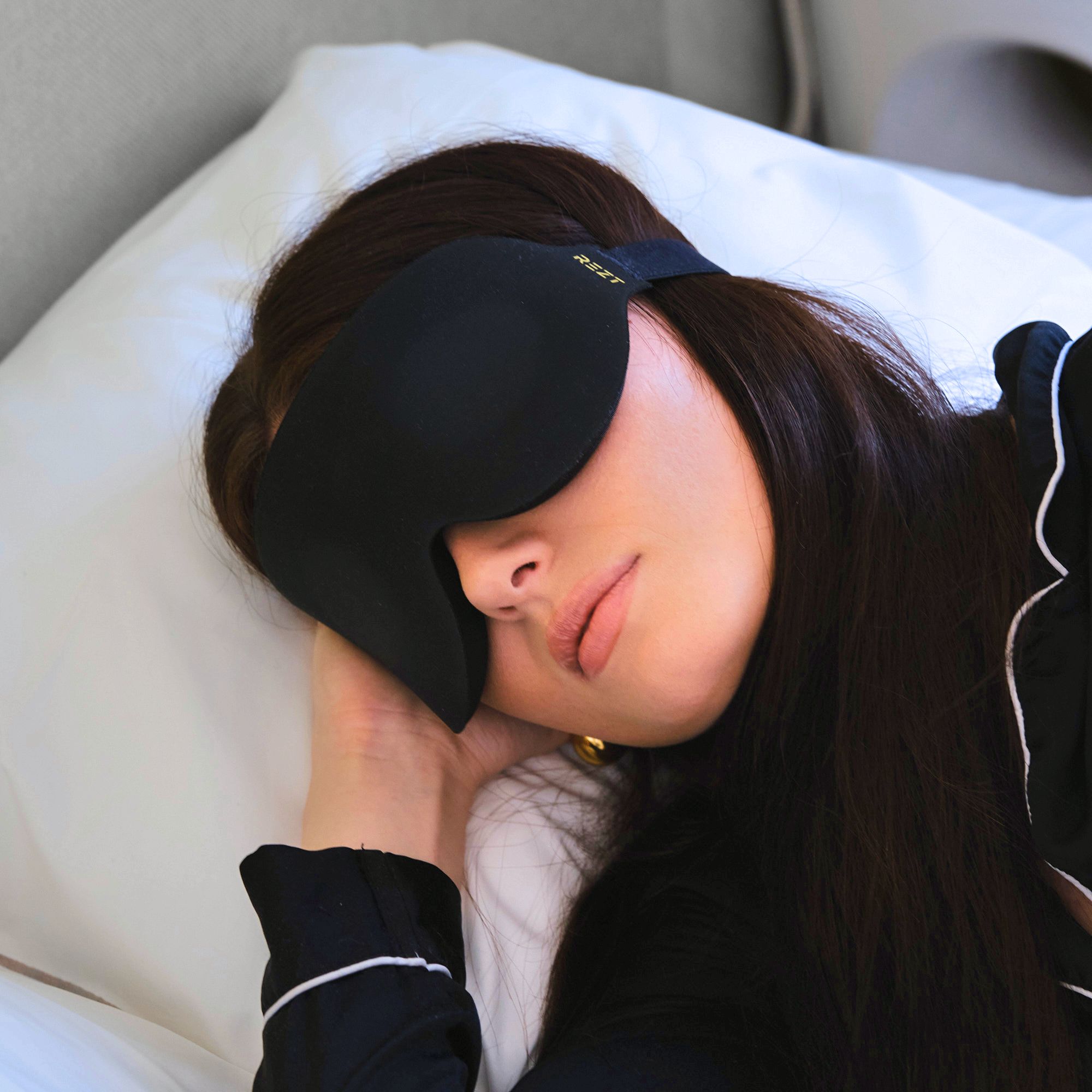 Kvinnan med svart Rezt sömnmask i säng - Bekväm design som inte trycker mot ögonen.