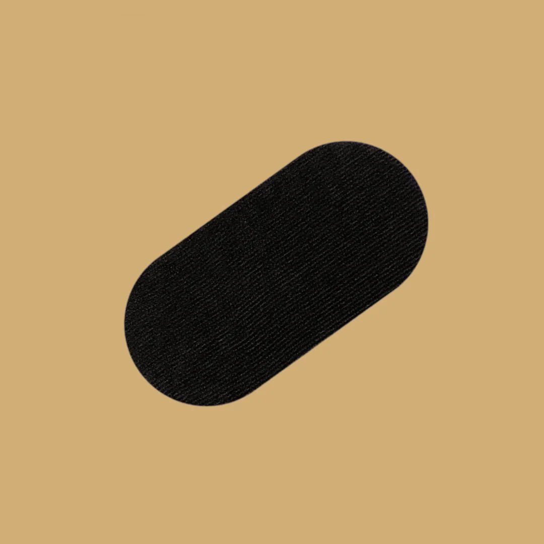 En enkel, oval REZT munntejp i svart, centrerad på en varm beige bakgrund. Tejpen är platt presenterad och texturen ser mjuk och behaglig ut, designad för att vara bekväm att använda medan man sover.